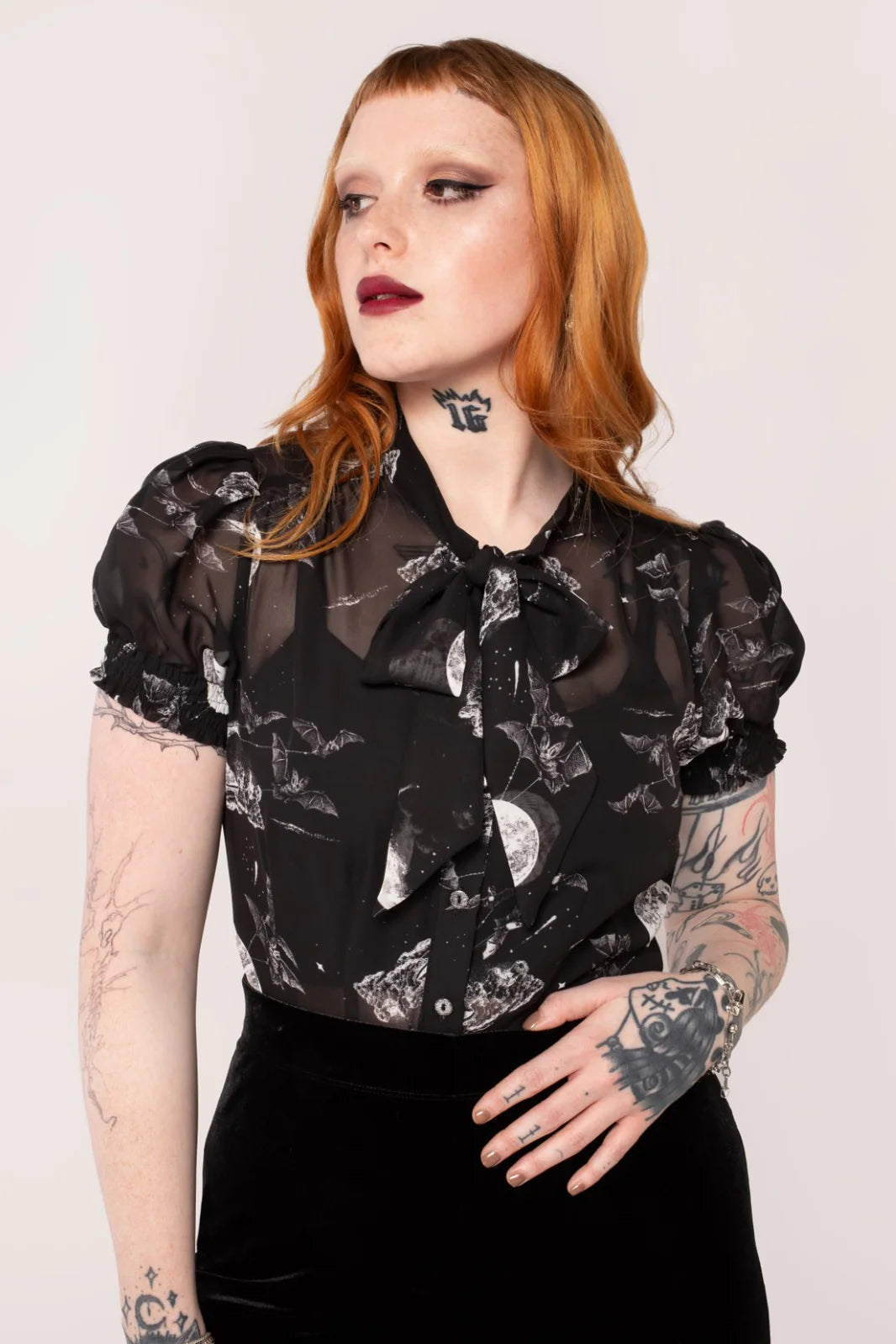 A model wearing an over the moon blouse with a black base and night sky scene, featuring short sleeves, a round neckline, and elasticated cuffs.
