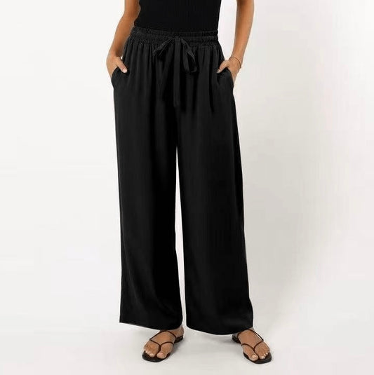 Person wearing black wide-leg pants on a white background