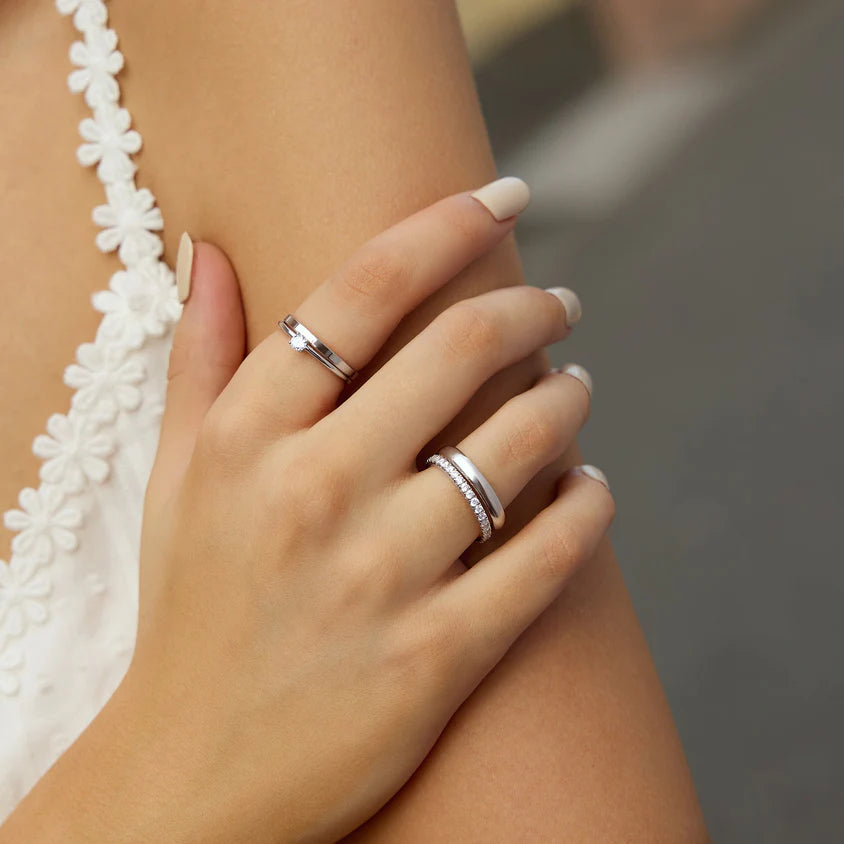 Close-up of a hand wearing two silver rings with a blurred background